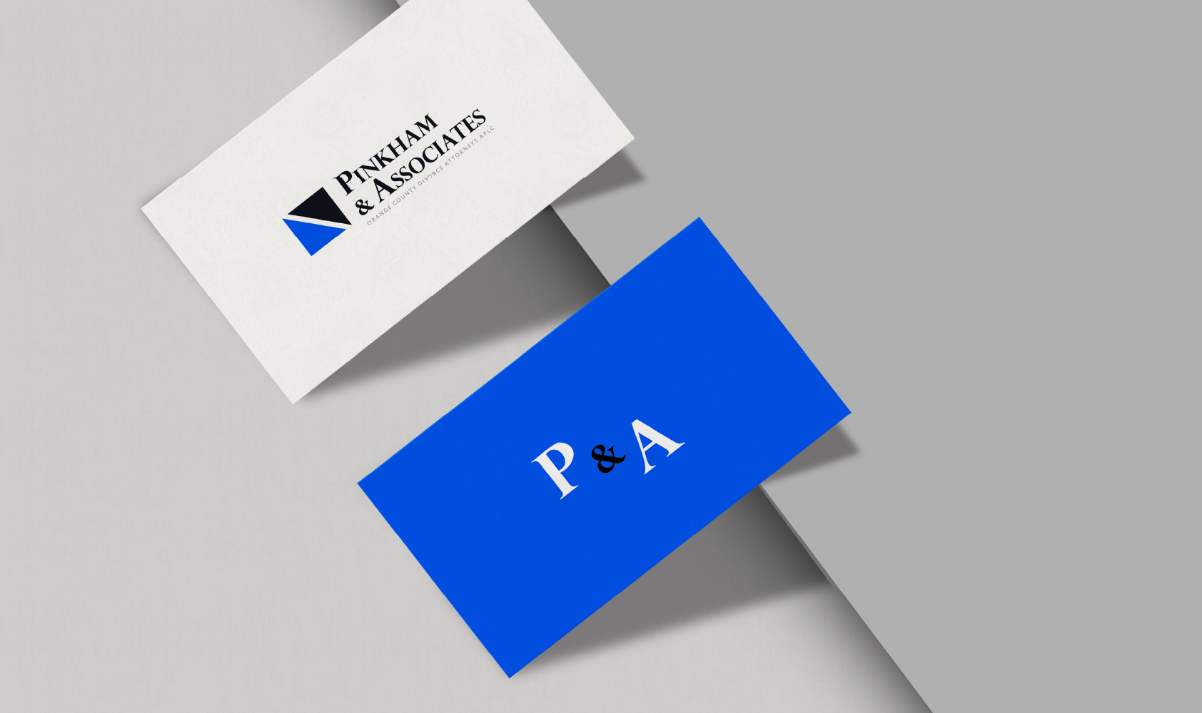 Two business cards: one white with a logo and Pynham & Associates, and one blue with P & A in white, both placed on a gray and white background.